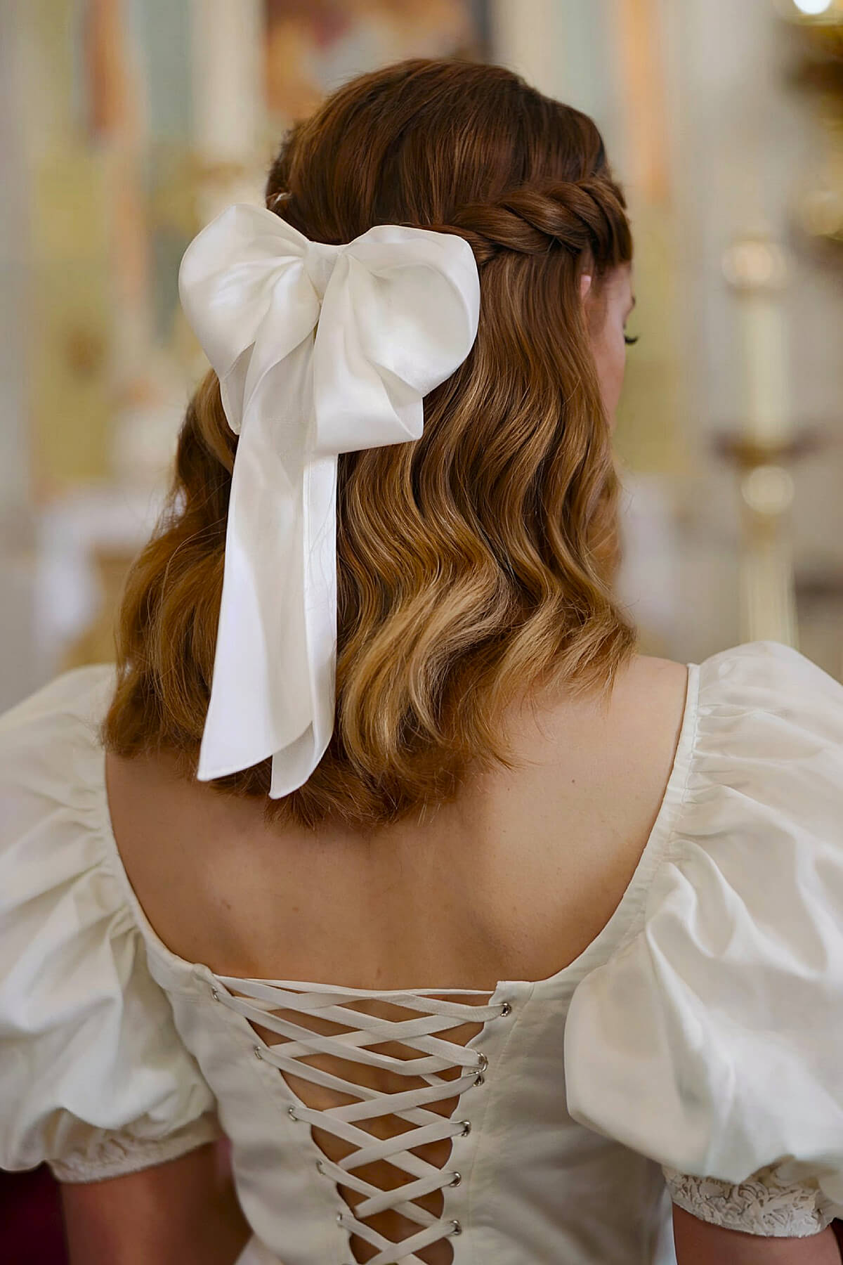 Half-up wedding hairstyle with waves and a satin bow