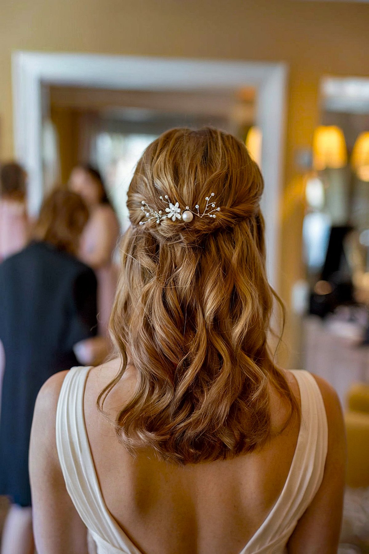 Half-up prom hairstyle with loose waves and a floral hairpin