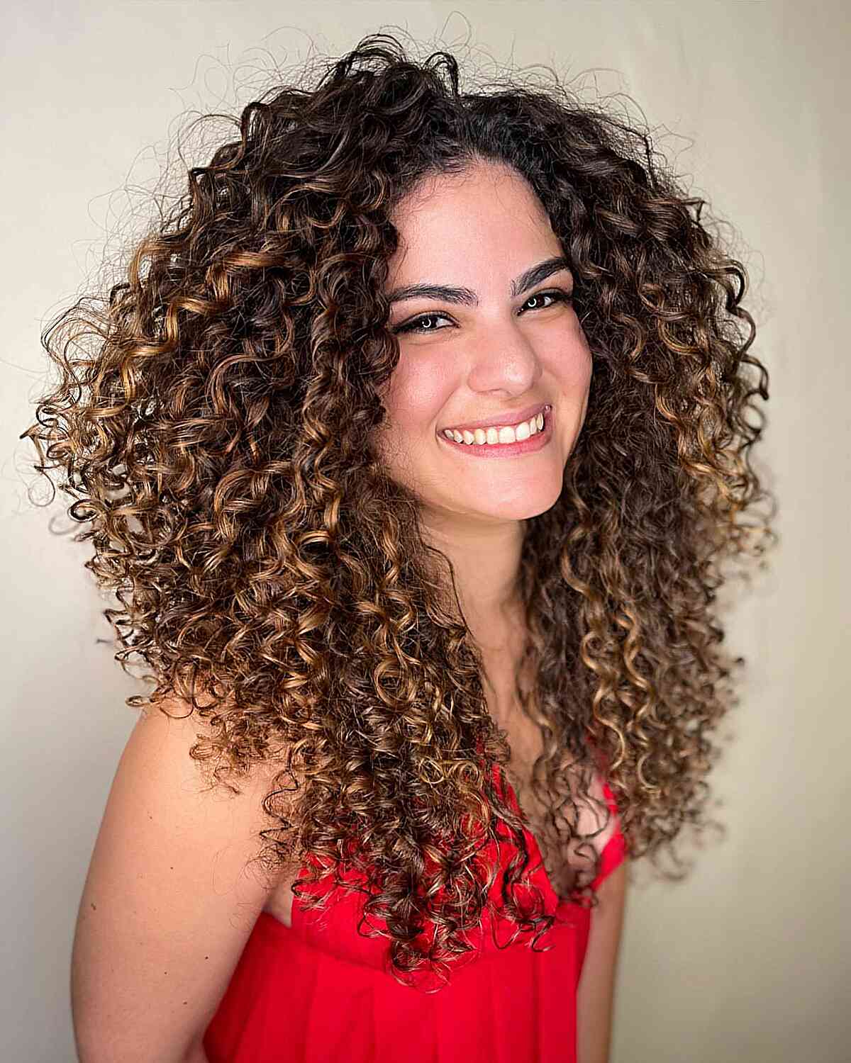 A woman with a Cadō cut featuring voluminous hair and layered curls, giving a lively and youthful appearance.