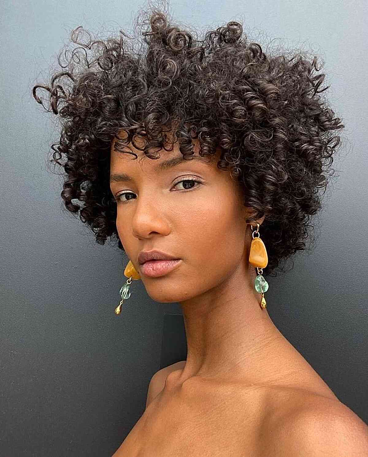 A woman with a Cadō cut on very short kinky hair, with layered curls adding structure and highlighting natural texture.