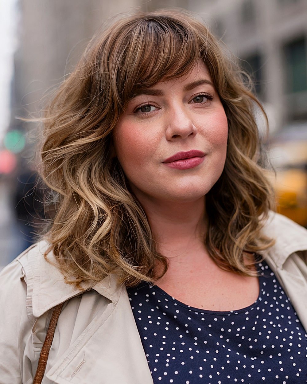 Medium layered hairstyle with airy texture and side-swept bangs for round-faced women over 40
