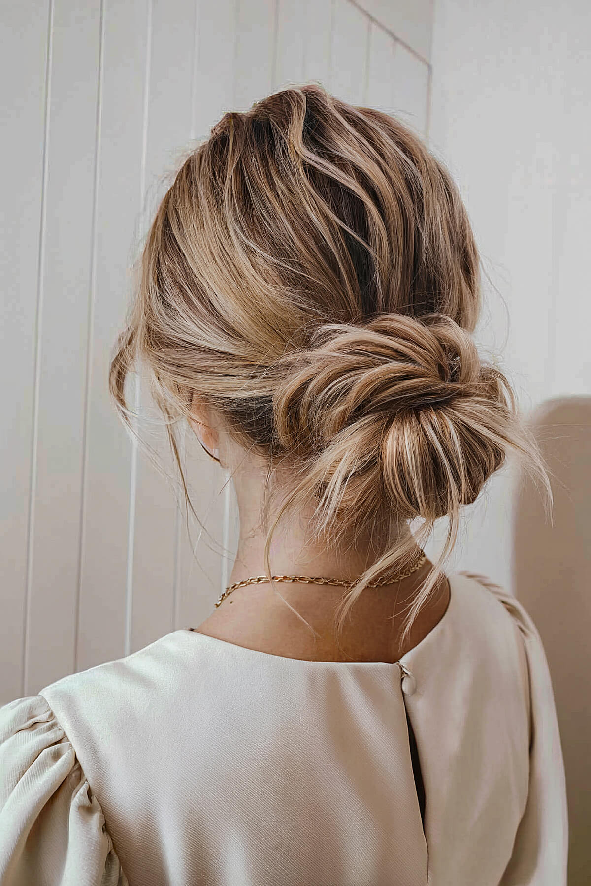 Easy low messy bun homecoming hairstyle with loose tendrils