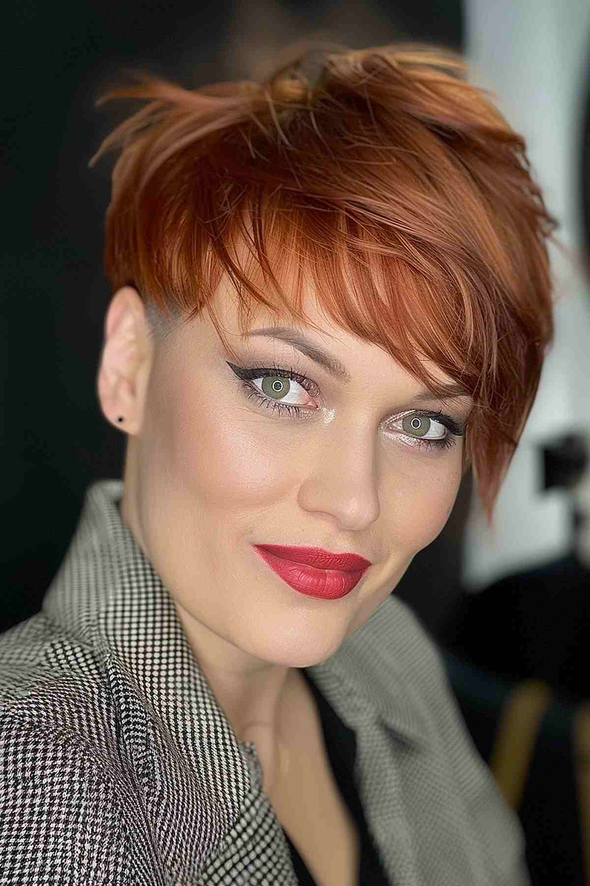 Woman with a vibrant red pixie cut featuring asymmetric bangs, projecting a bold and dynamic appearance.