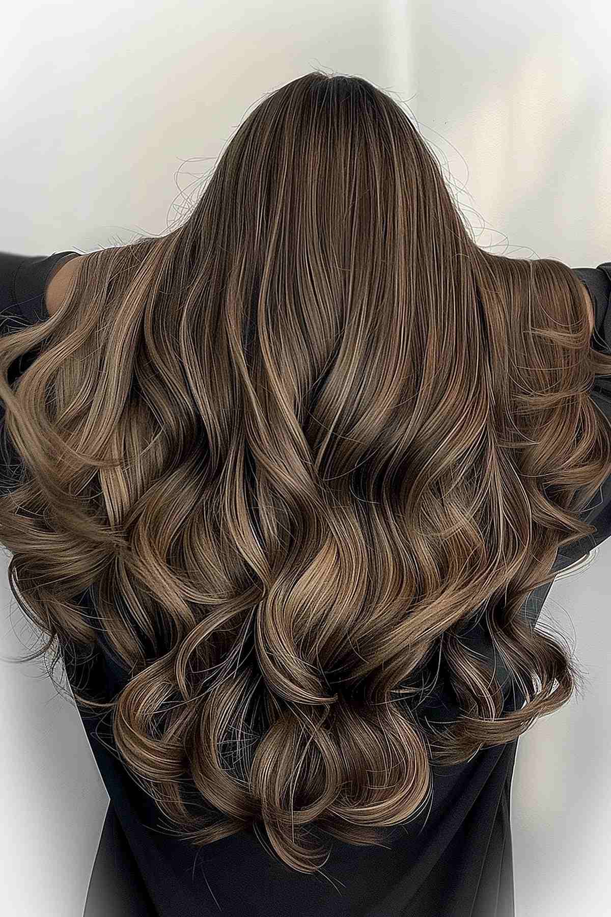 Luxurious long waves with a balayage technique on mushroom brown hair, highlighting depth and movement with expert color blending.