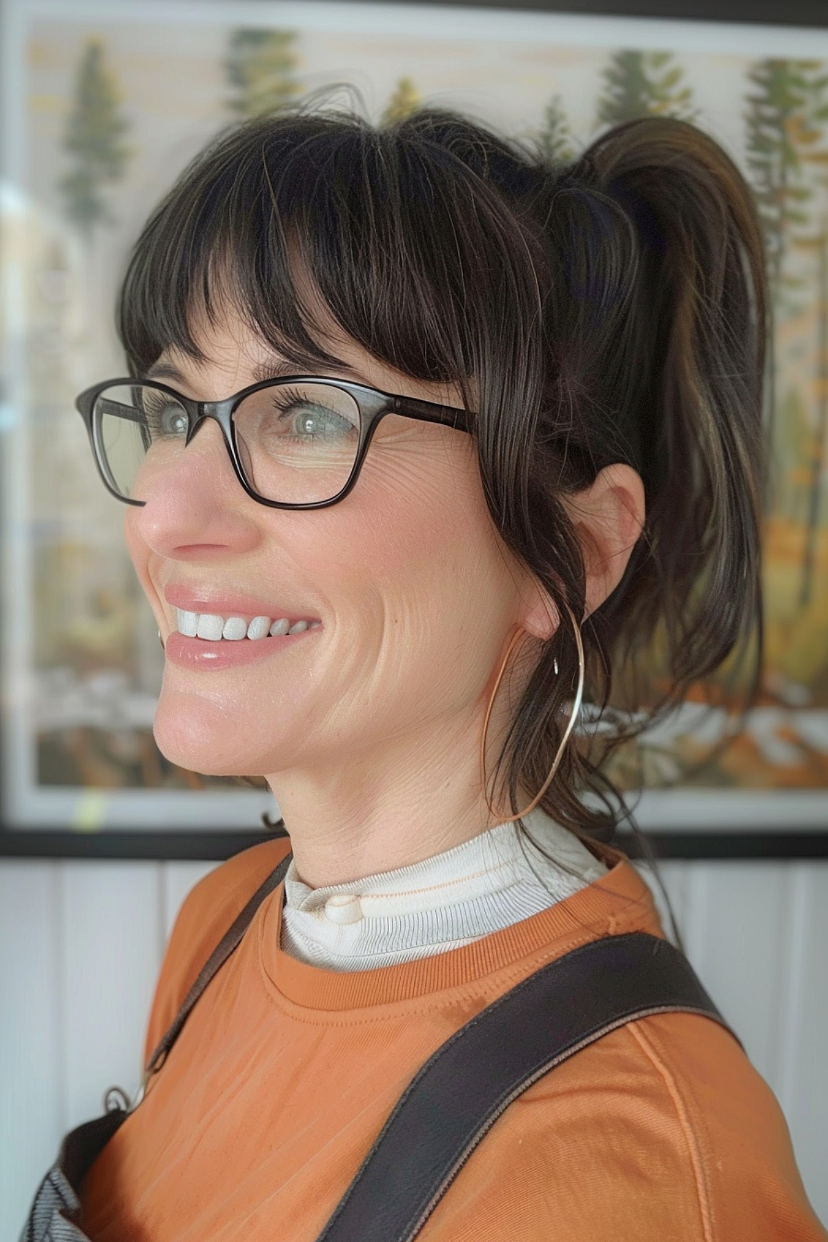 A woman with a high ponytail and straight bangs, and glasses that match her long face.