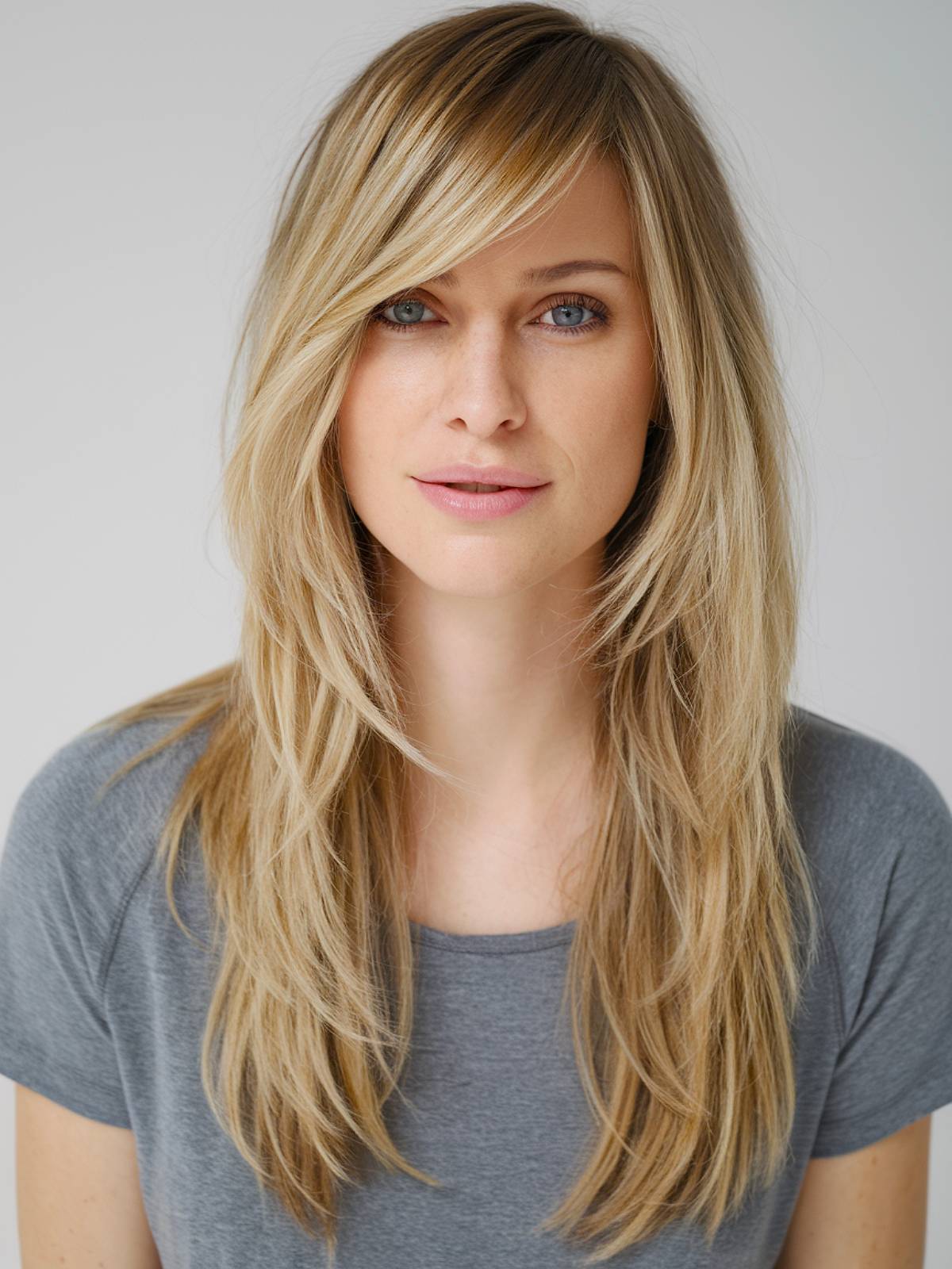 Blonde long layered haircut with side bangs and face-framing highlights for added dimension