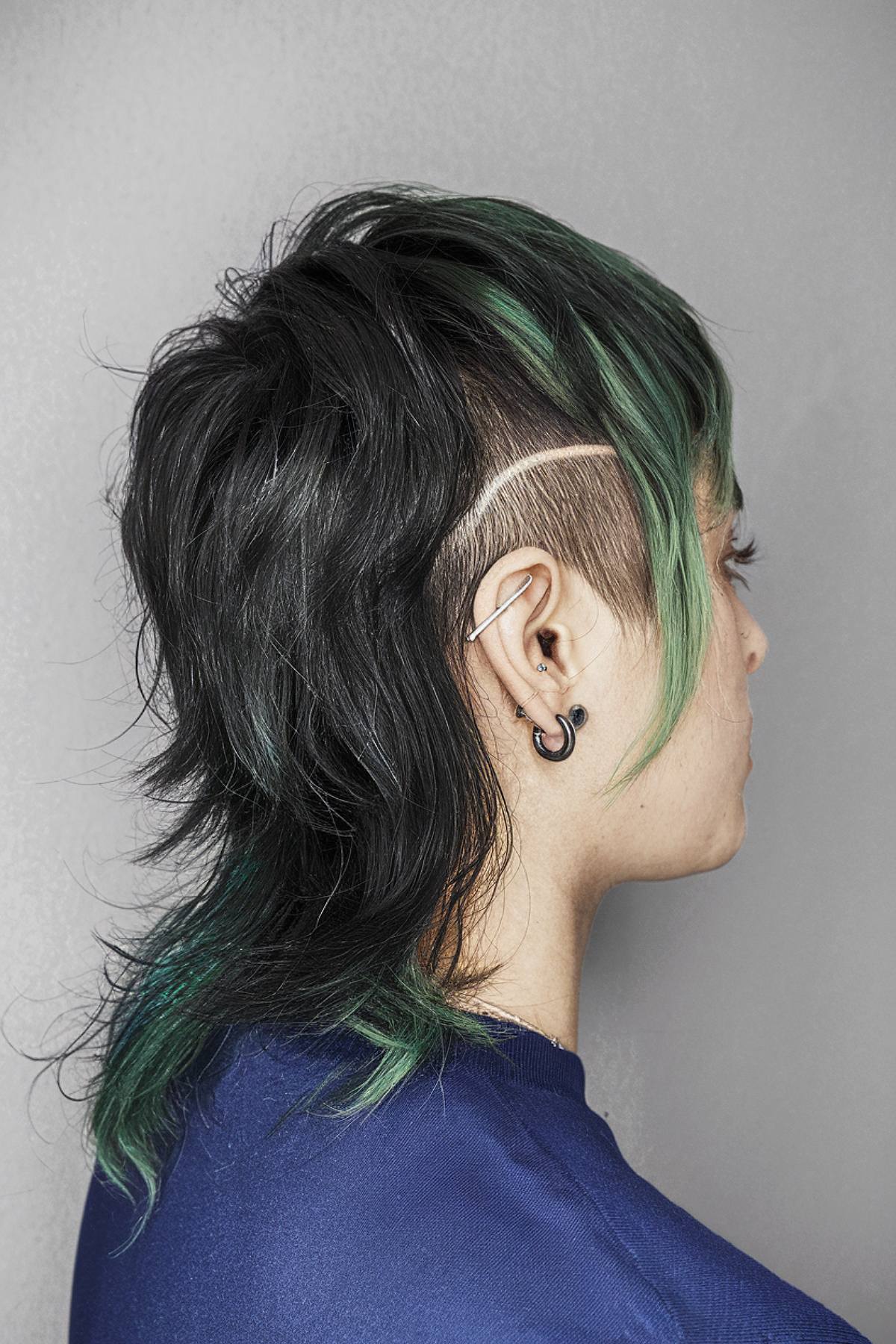 Queer-style medium length layered haircut with green highlights