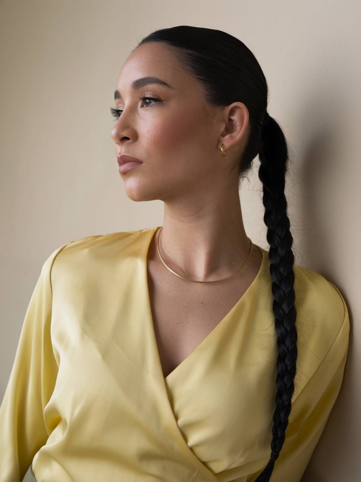 A sleek, low braided ponytail with a sharp middle part, creating a timeless Latina hairstyle