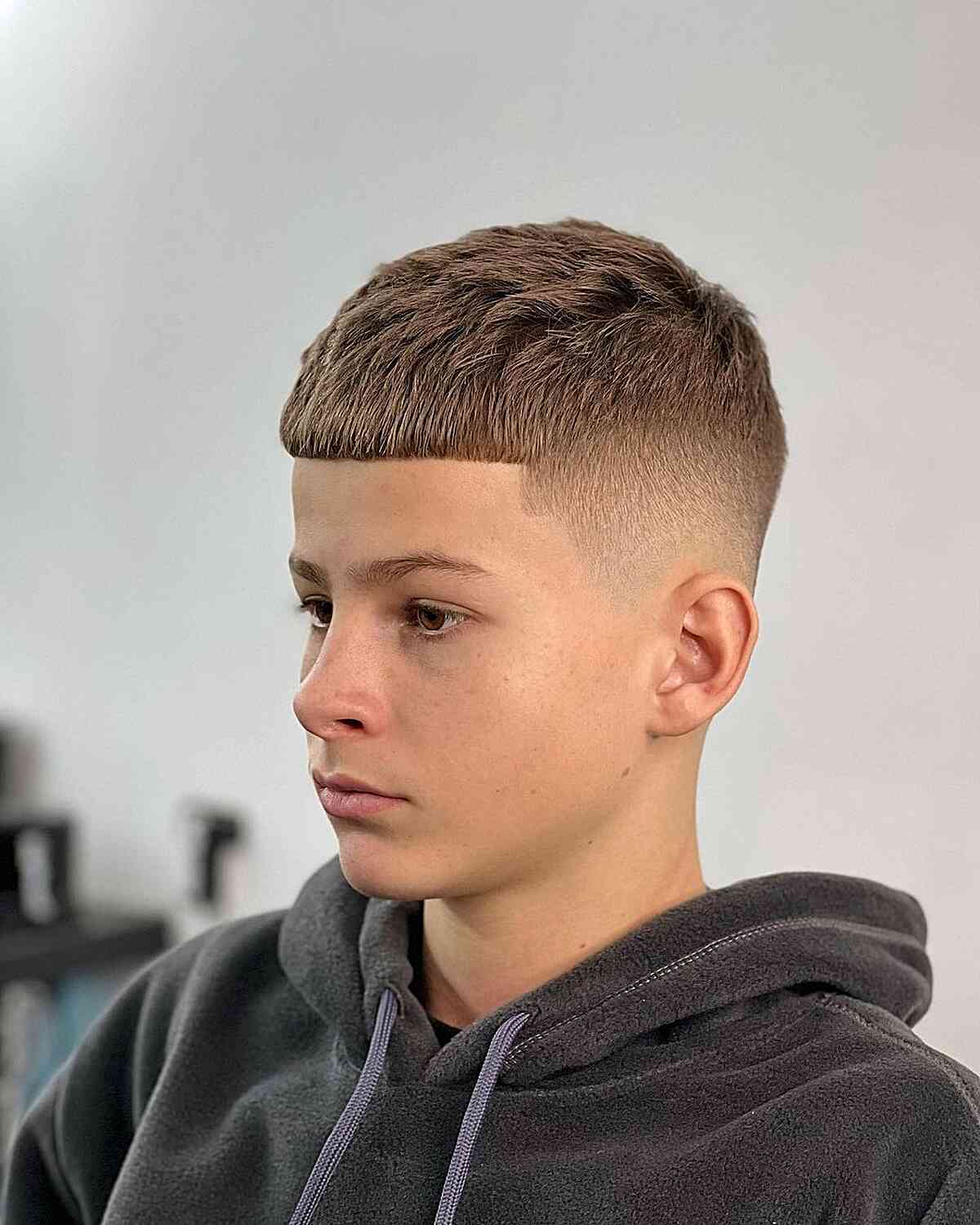 Brushed Forward Fade Cut for Teen Boys with a bald fade on the sides and back