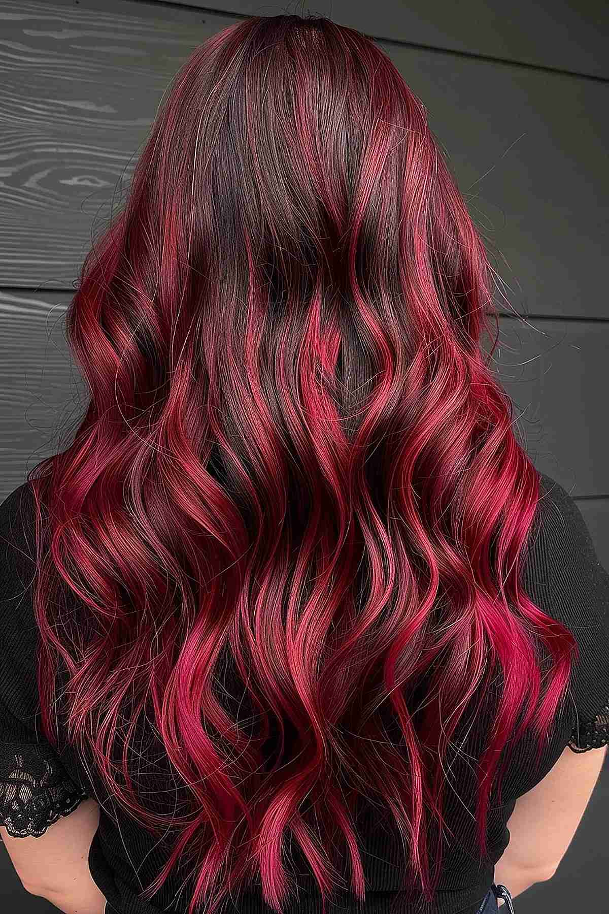 Cherry red balayage on long hair creating a seamless color transition.