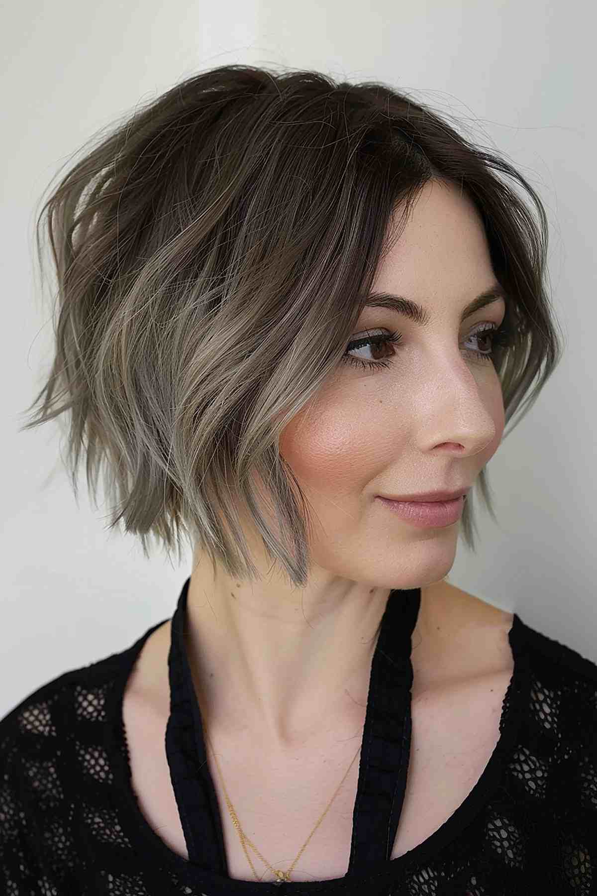A chin-length, uneven bob in ash brown with uneven layers and subtle highlights.