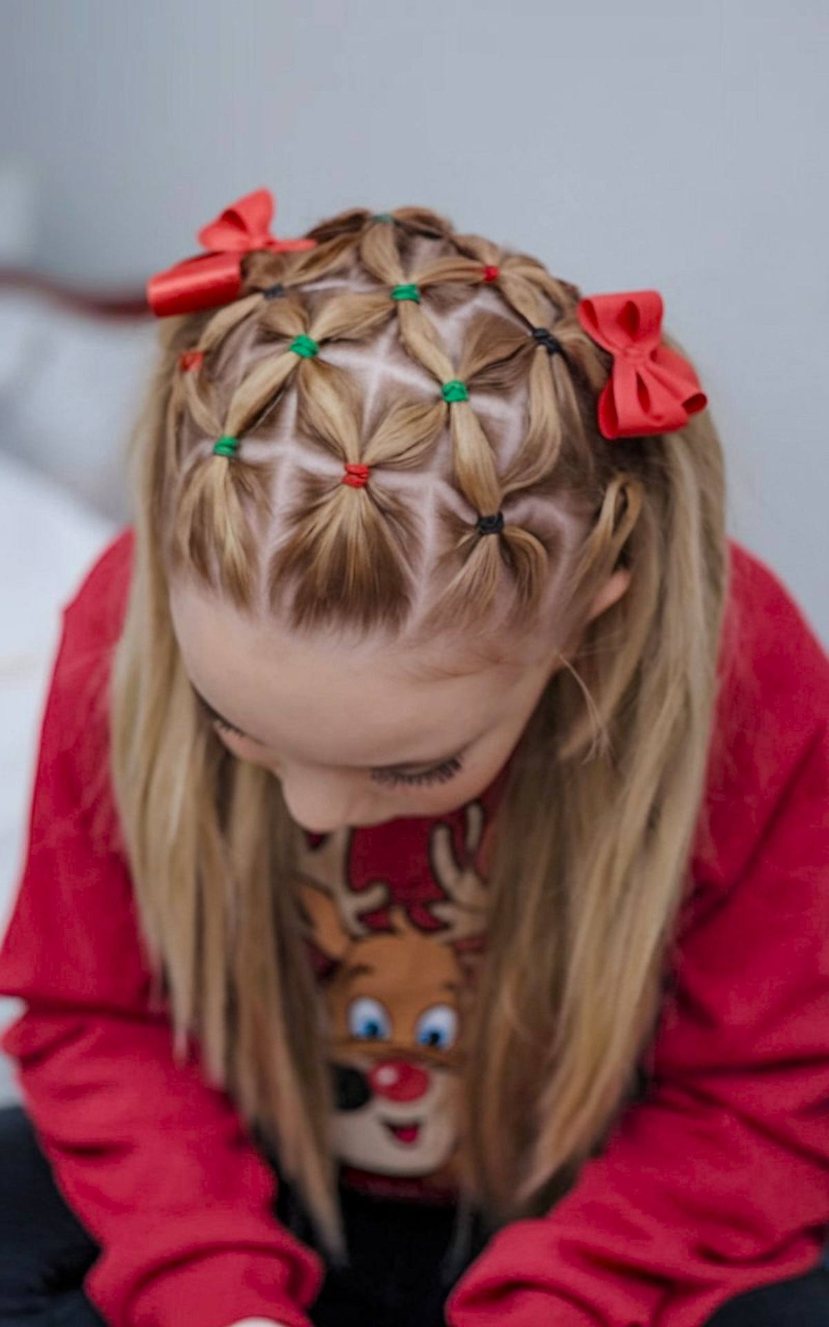 Criss-cross ponytail with red and green elastics and bows for a Christmas hairstyle