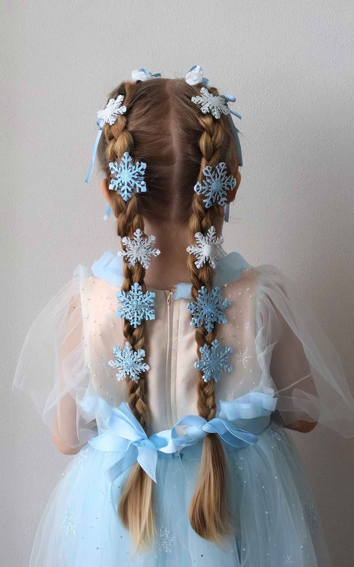 Double braids decorated with blue snowflakes and ribbons for a winter-themed Christmas hairstyle