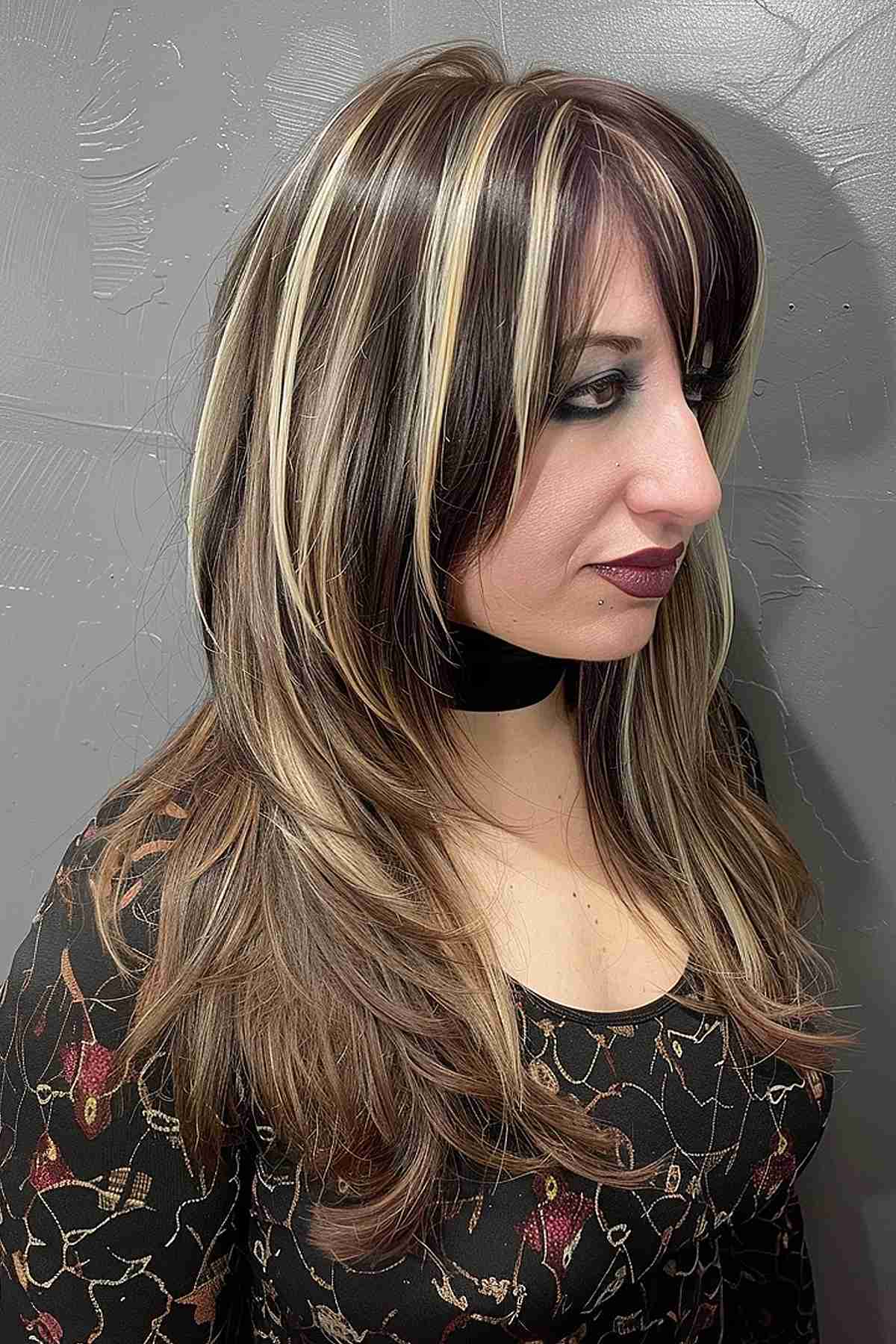 Medium-length black hair with blonde highlights and soft layers