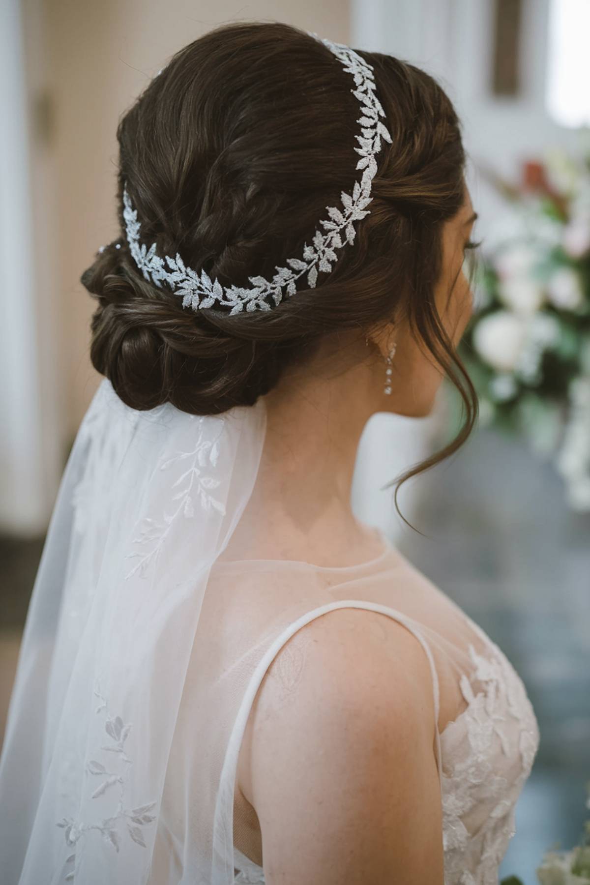 Braided wedding updo with a silver headpiece and veil