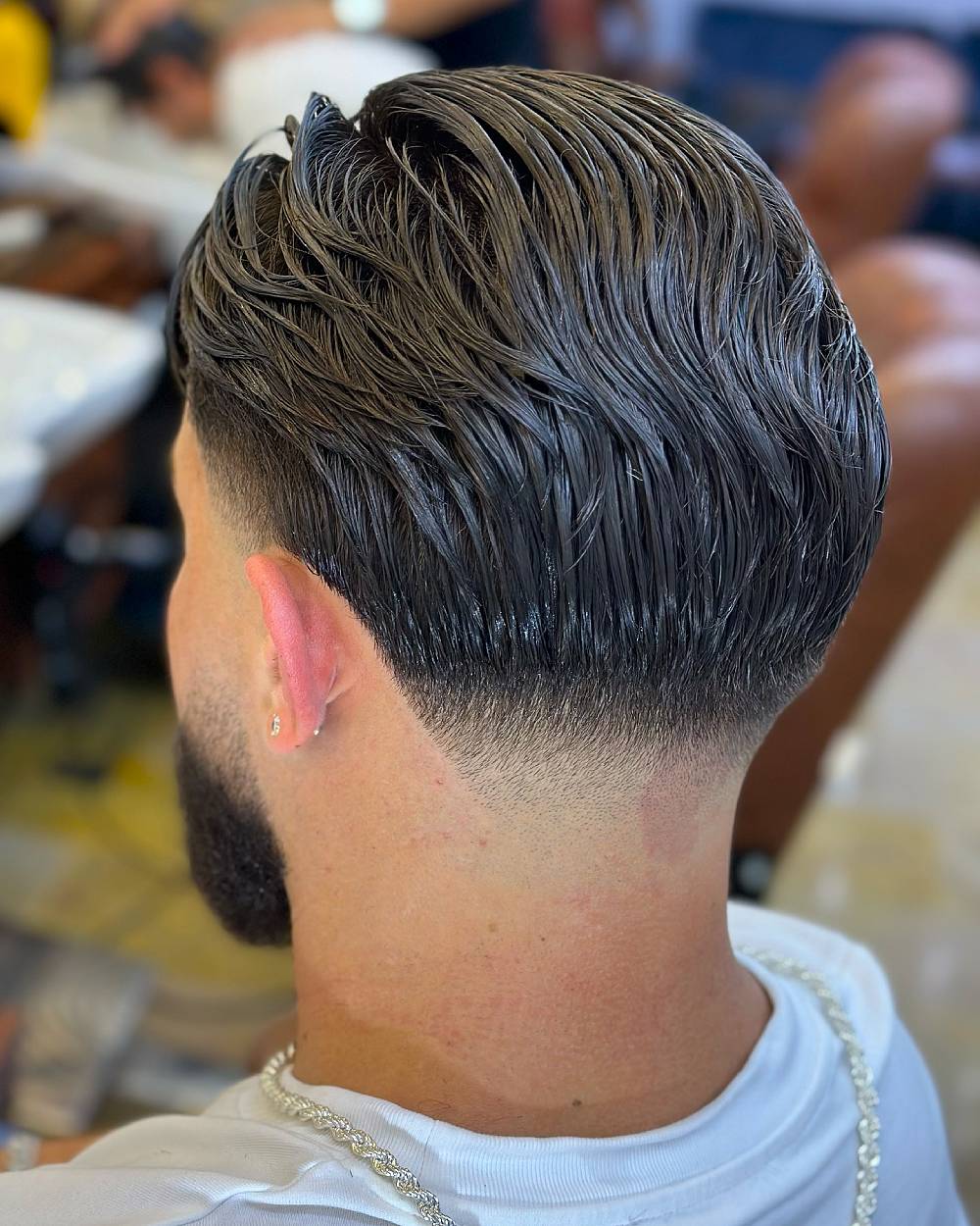 Classic slick back hairstyle with skin taper fade, ideal for men wanting a polished, sharp, and professional look