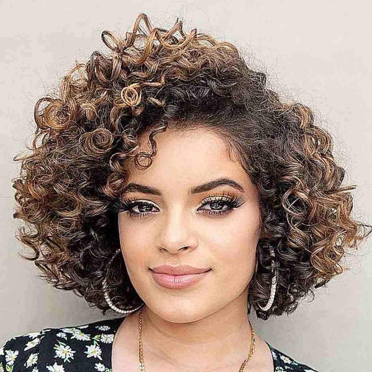 Curly bob with side-swept styling, mixing caramel and espresso tones, with a round cut that balances angular features.
