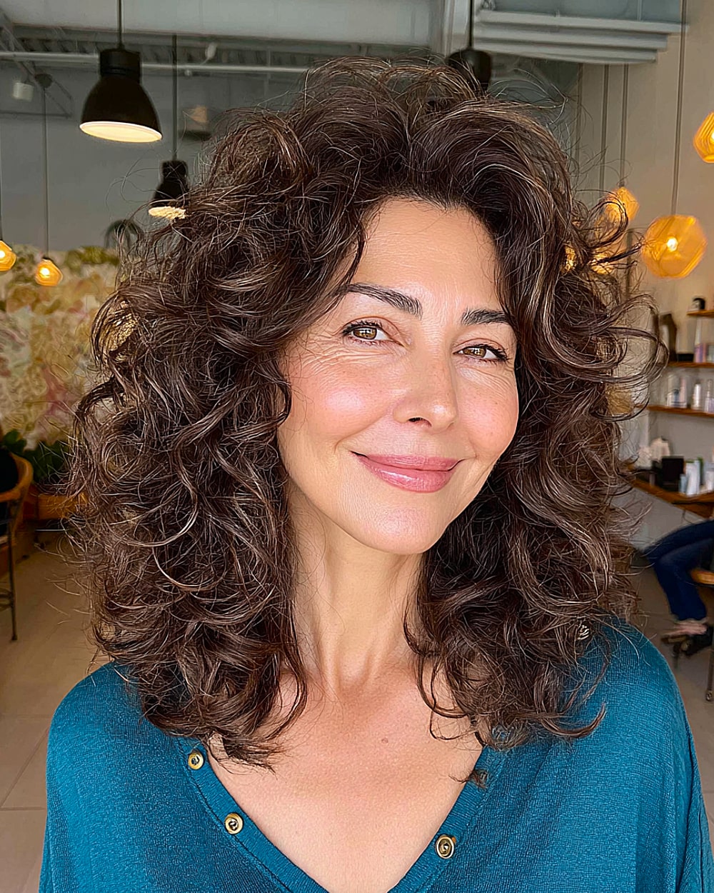 Bouncy layered curls with volume for women over 50 with thick, dark, shoulder-length curly hair