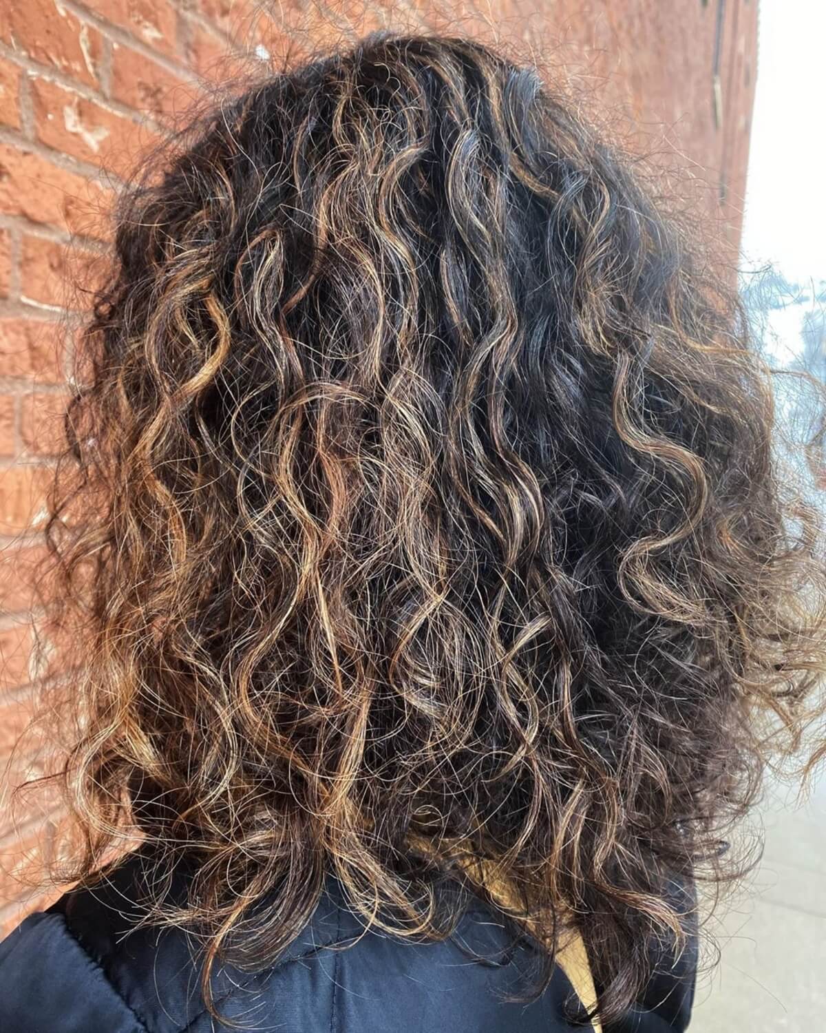curly dark brown hair with caramel highlights