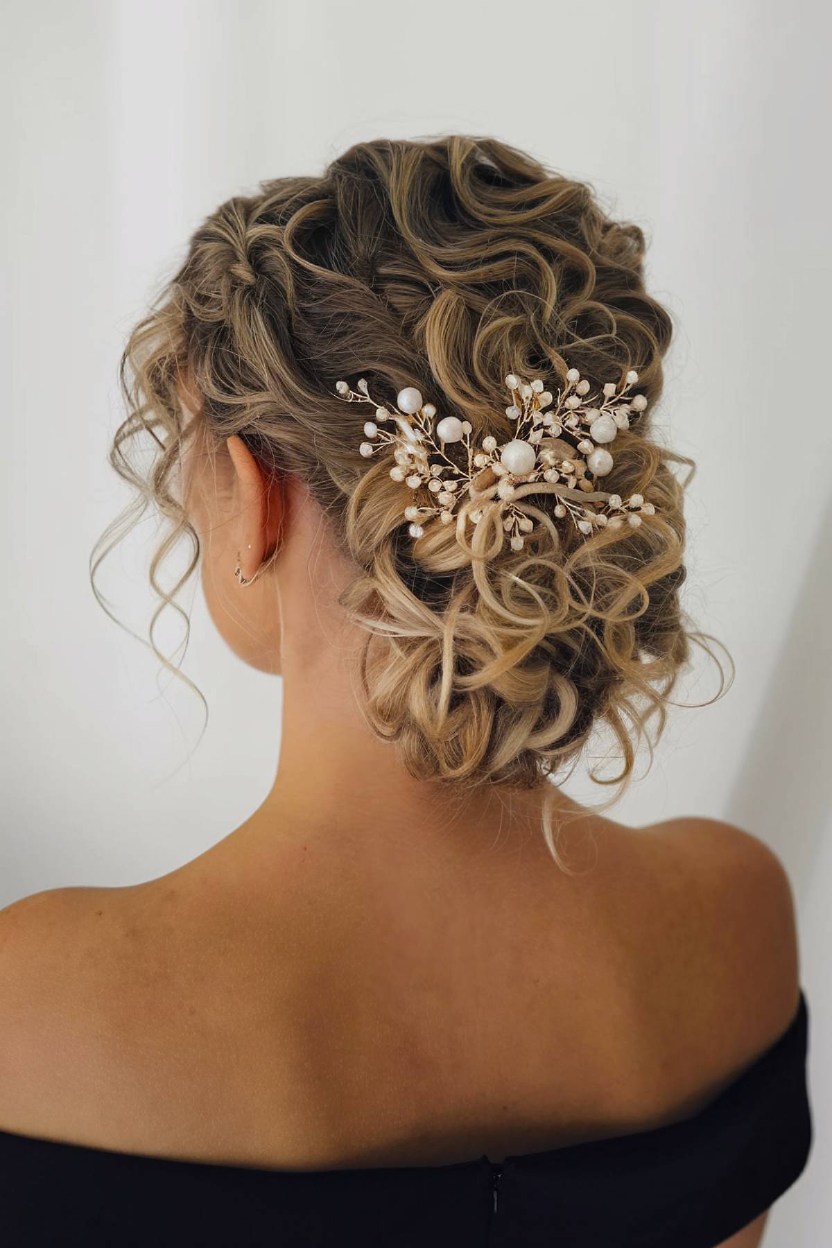 Curly bun featuring pearl-embellished decorative hair jewelry for a sophisticated look