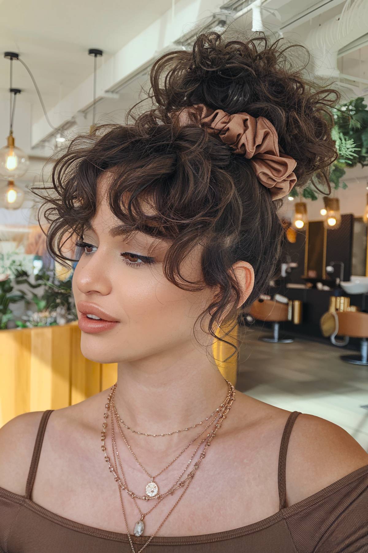 Curly bun with wispy, soft bangs for a playful and modern look