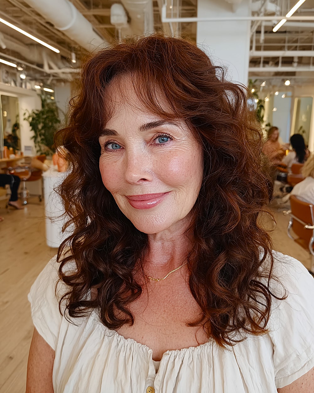 Medium curly hairstyle with curtain bangs and soft volume for women over 50