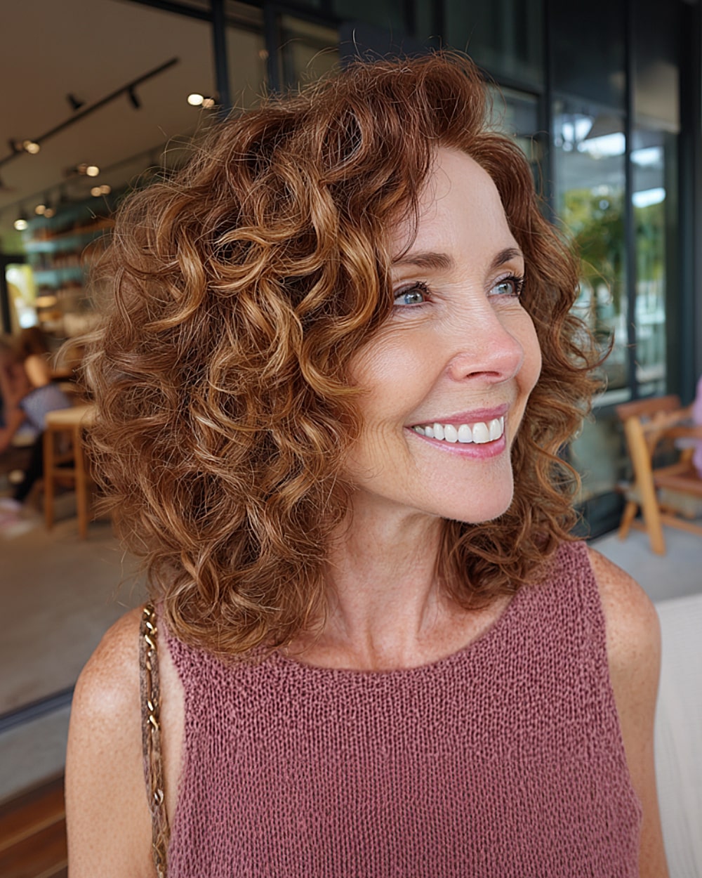 Shoulder-length layered curls with subtle copper highlights for older women