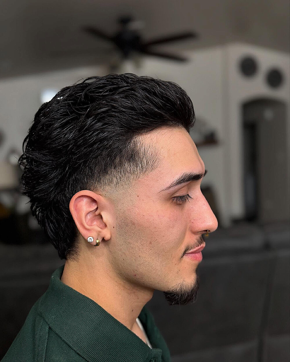 Curly mullet with low taper fade on sides for a bold and trendy men’s haircut.