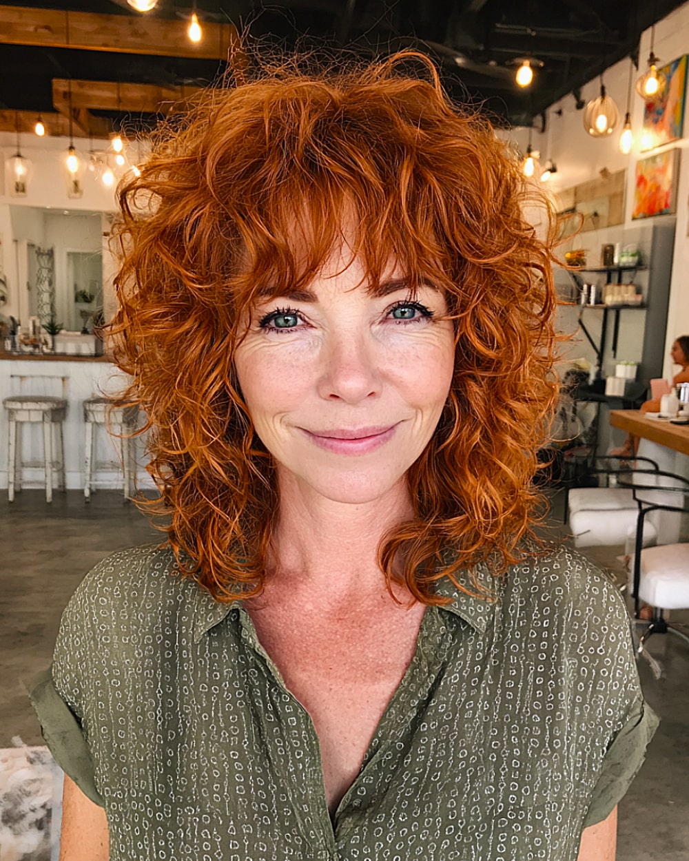 Curly shag haircut with tousled texture and bangs for women over 50 with red hair
