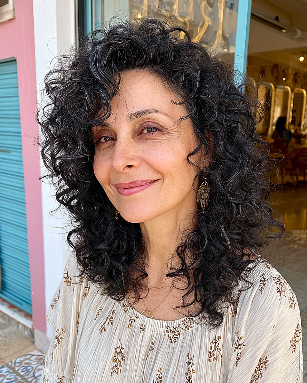 Side-parted medium curly hairstyle with volume for mature women with thick dark curls