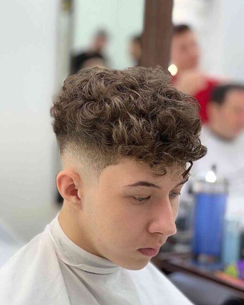 A Curly Top with Curly Bangs for Teen Boys with a skin fade