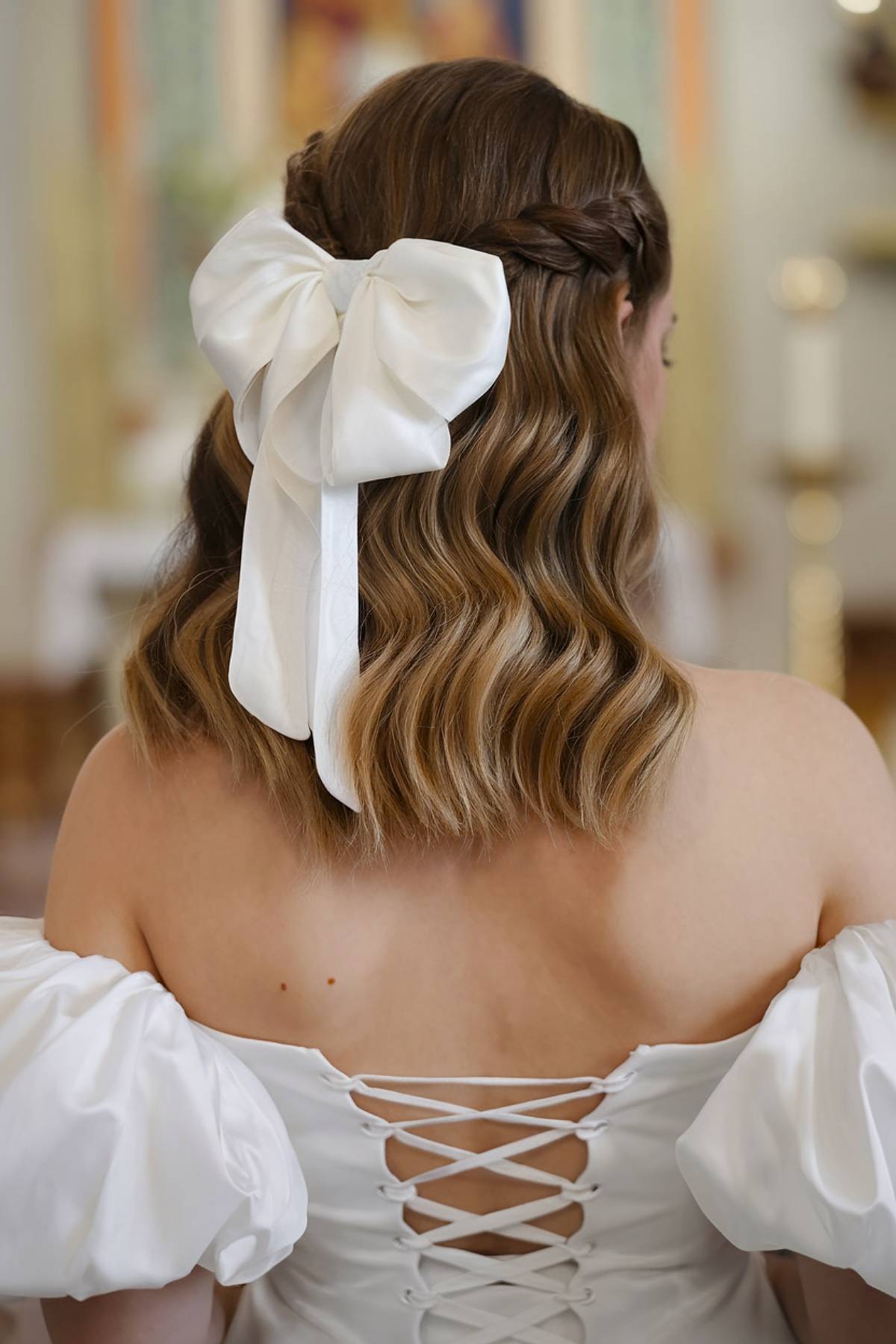 Half-up wedding hairstyle with waves and a satin bow