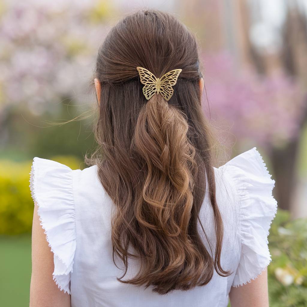 Half-up spring hairstyle with loose curls and gold butterfly clip on medium brown hair