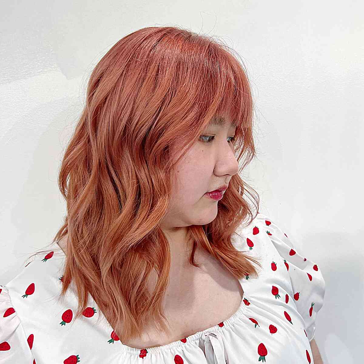 Darker Rose Gold hair color on collarbone length hair Paired with Bangs