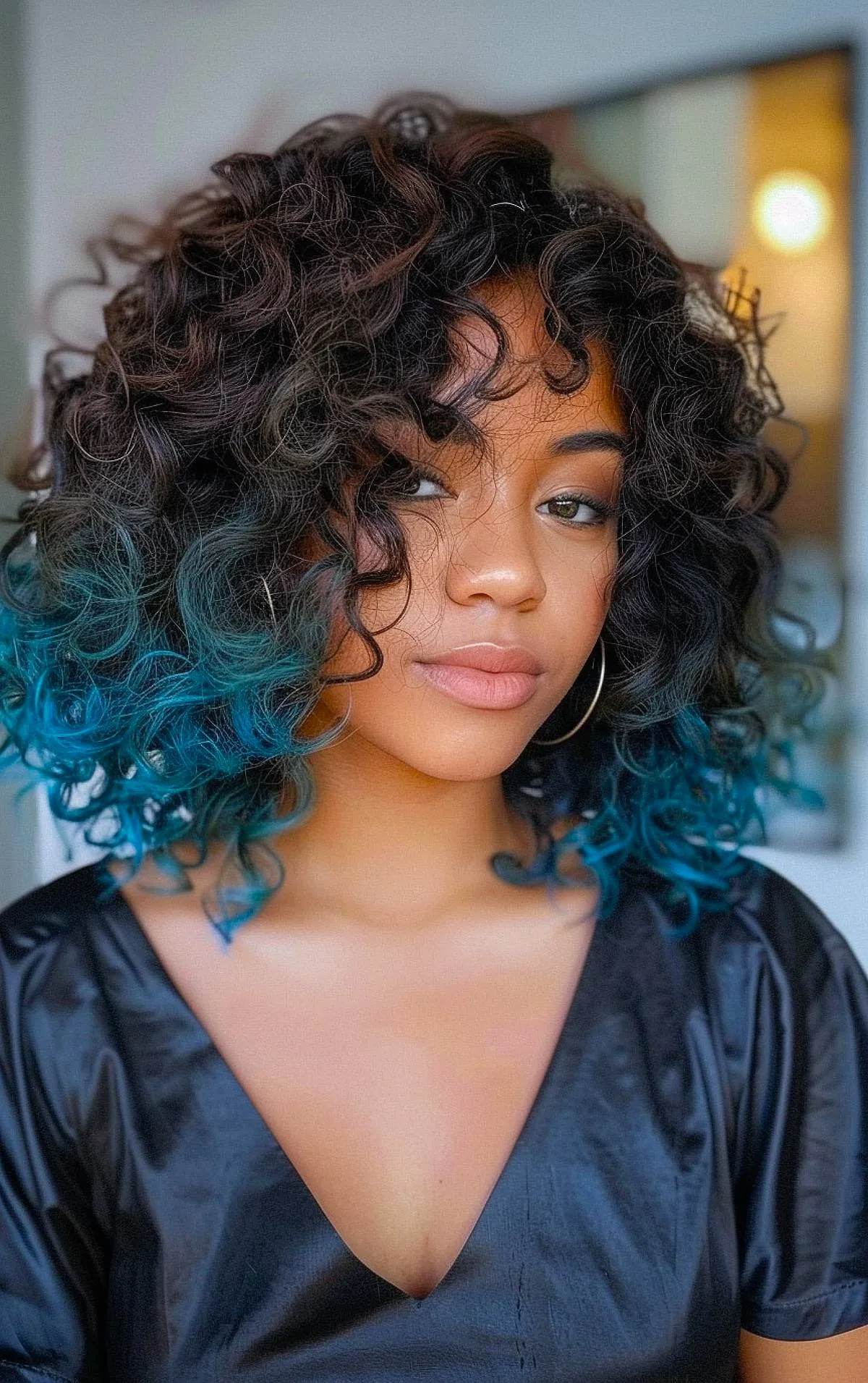 Curly dark hair with teal blue dip-dye ends for a fun, colorful look