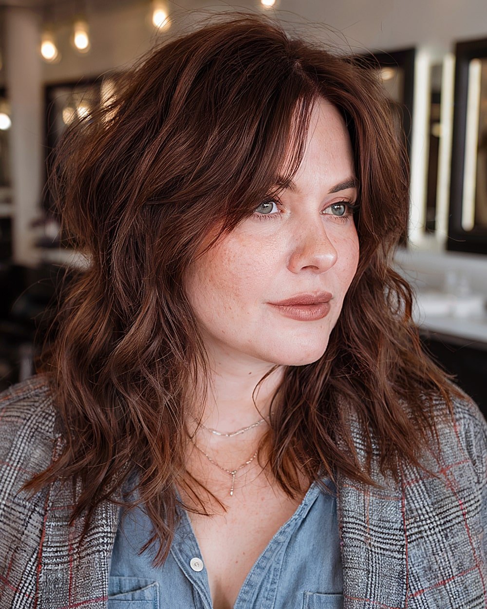 Medium layered brunette haircut with disconnected texture and soft volume for round faces over 40