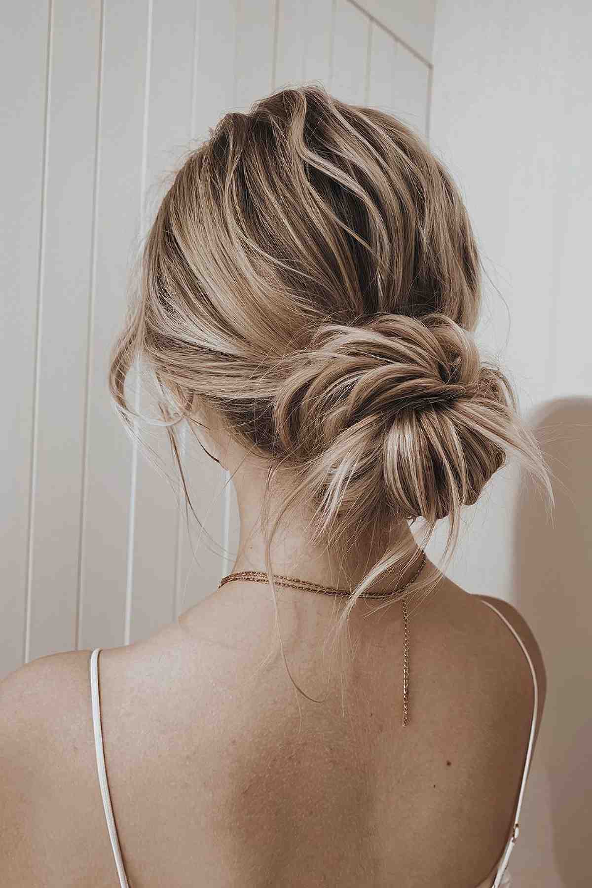 Easy low messy bun homecoming hairstyle with loose tendrils