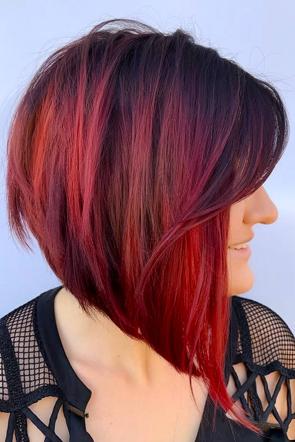 Edgy angled bob haircut with vibrant red tones and layers