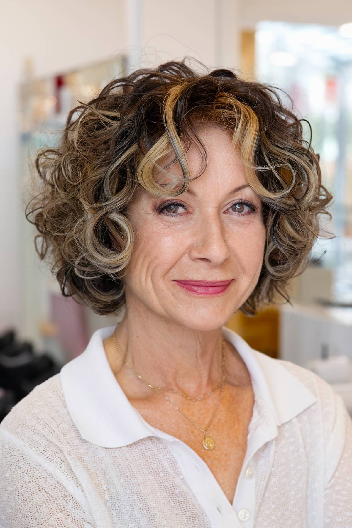 Classic curly bob hairstyle for older women with blonde highlights above shoulders