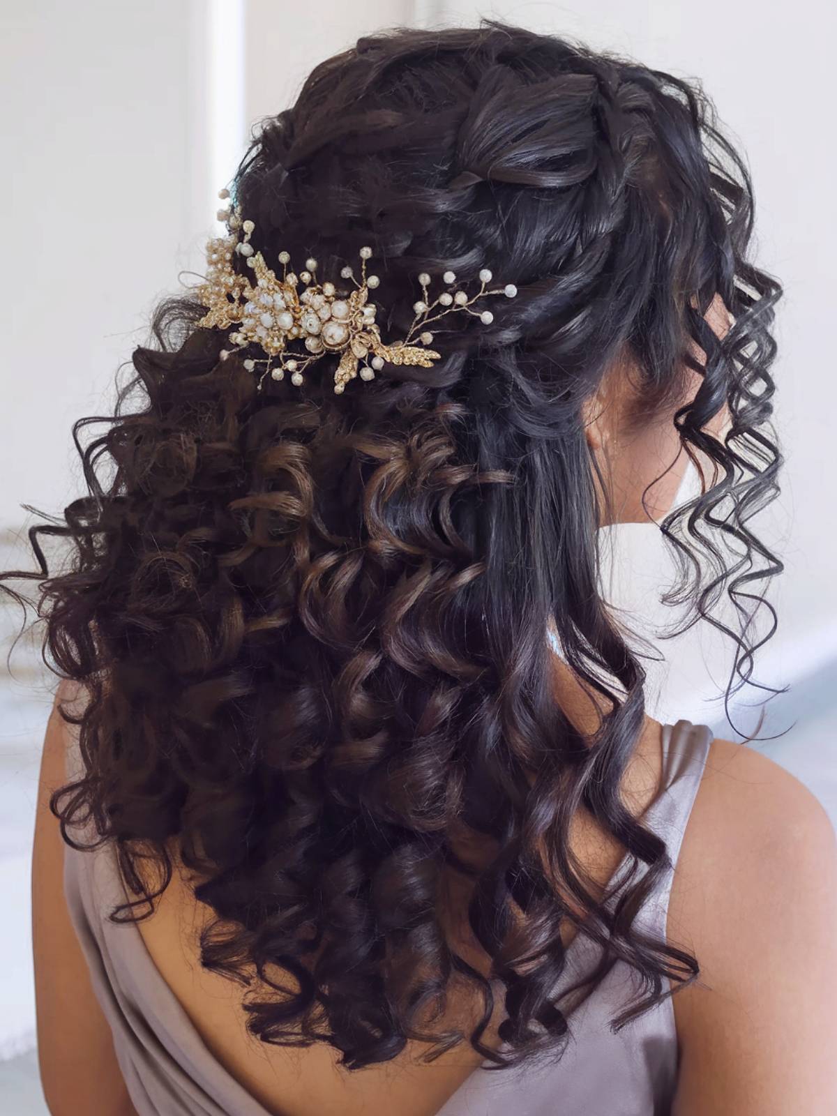 Curly half-up wedding hairstyle with pearl accessory