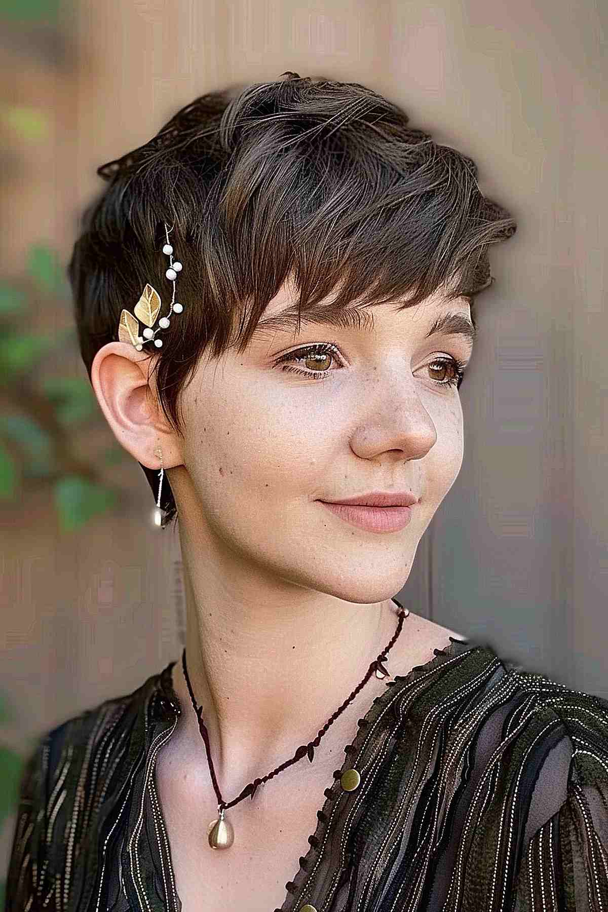 Fairy-inspired short elf crop haircut with soft, wispy bangs and decorative hairpin.