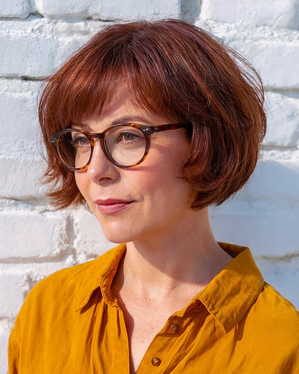 Short maple-toned bob with textured ends and soft fringe, ideal fall hairstyle for fine hair and glasses