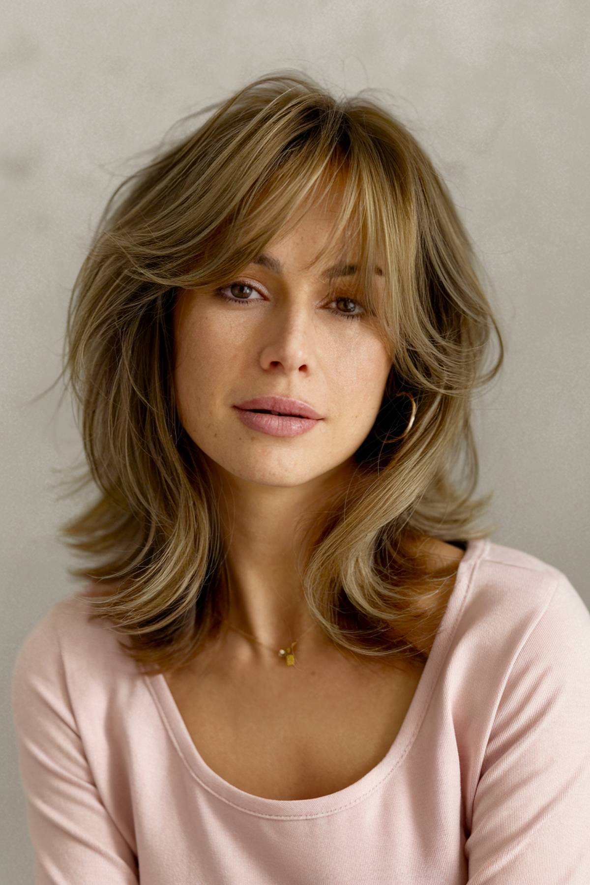 Medium-length layered haircut with soft feathered ends and curtain bangs