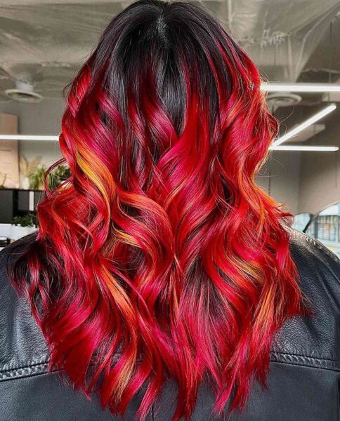 a Fiery Red Balayage on long wavy hair with black roots