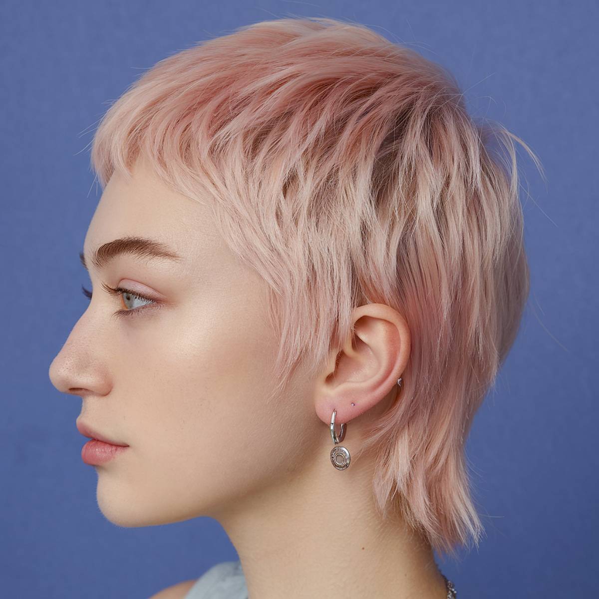 Rose gold pixie cut with mullet-inspired layers and textured bangs for a bold, edgy style