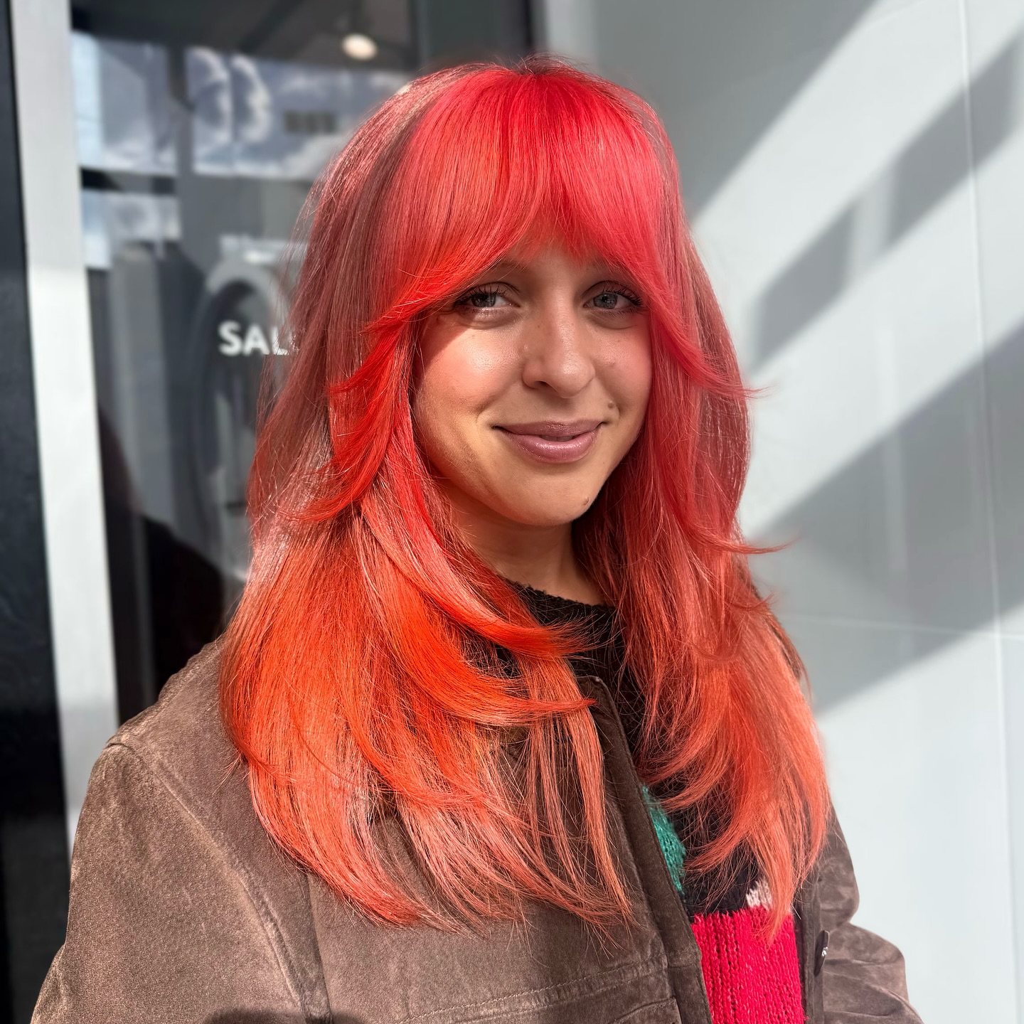 Vibrant Coral Layers with Soft Face-Framing Bangs