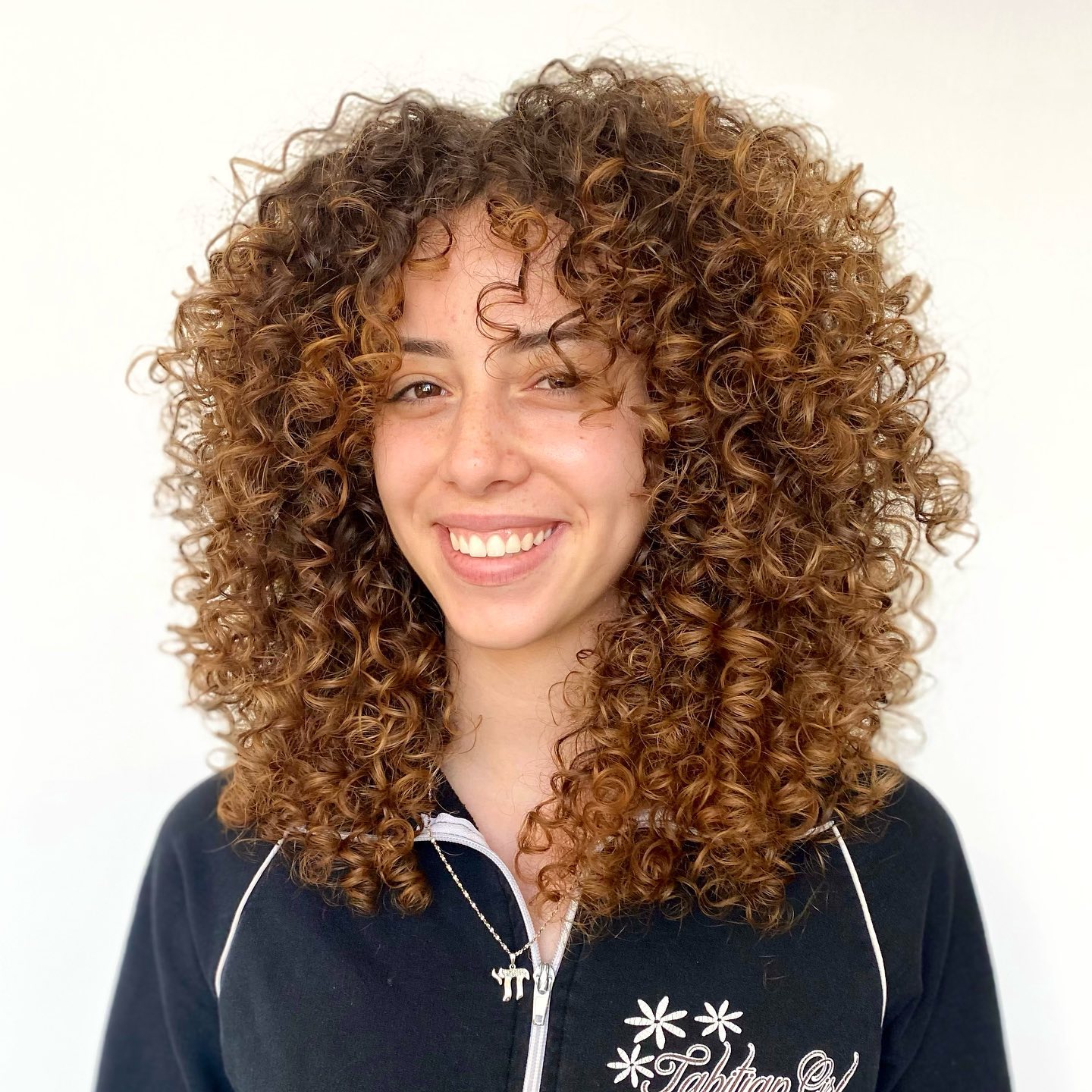 Dynamic Curly Face-Framing Style with Warm Highlights