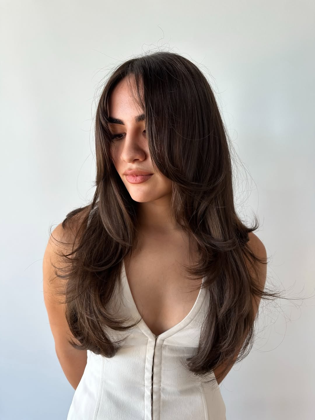 Corte em cascata castanho elegante com camadas suaves e volumosas.