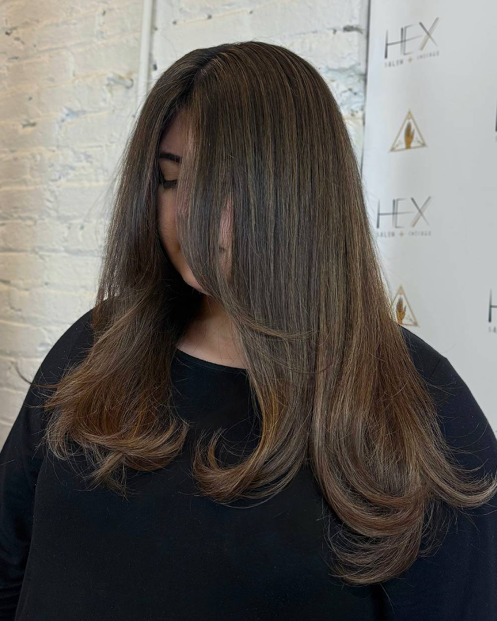 Morena de cabello color latte de lujo con suaves capas que enmarcan el rostro