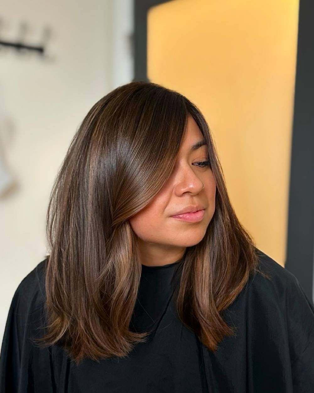 Castaño latte con suaves capas y reflejos que enmarcan el rostro